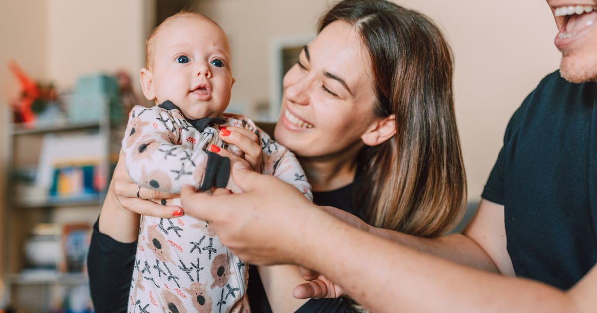 Родители държат бебето си вкъщи и се усмихват